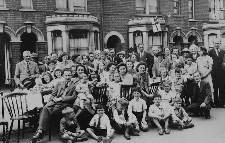 A nostalgic black and white image of a large group celebrating on a British street. Perfect for historical or community themes.