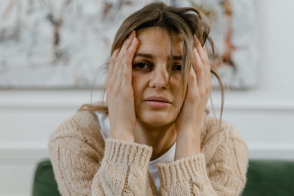 Woman looking distressed with hands on head, expressing worry indoors.
