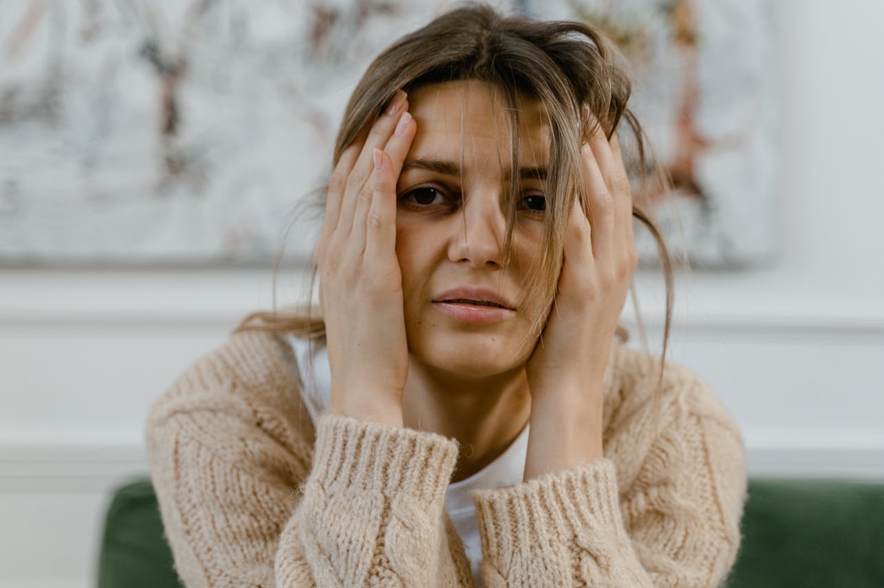Woman looking distressed with hands on head, expressing worry indoors.