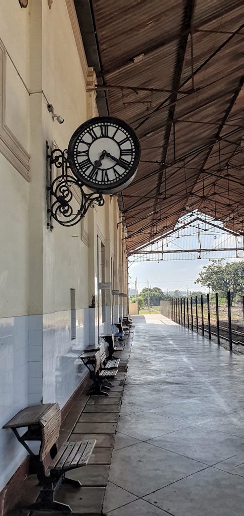 A vintage railway station platform featuring a retro-style wall clock with benches lining the walkway.