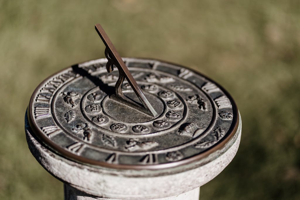 Close-up of a classic sundial with Roman numerals and zodiac signs in a garden.