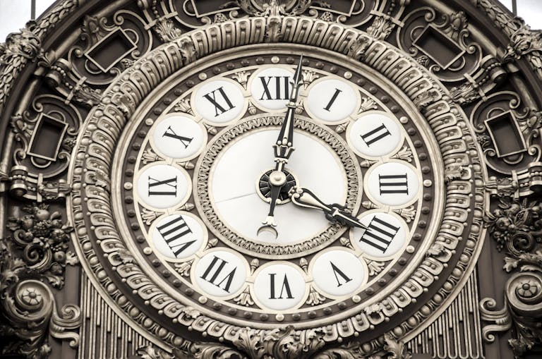 Close-up of an ornate clock face featuring Roman numerals and intricate details.