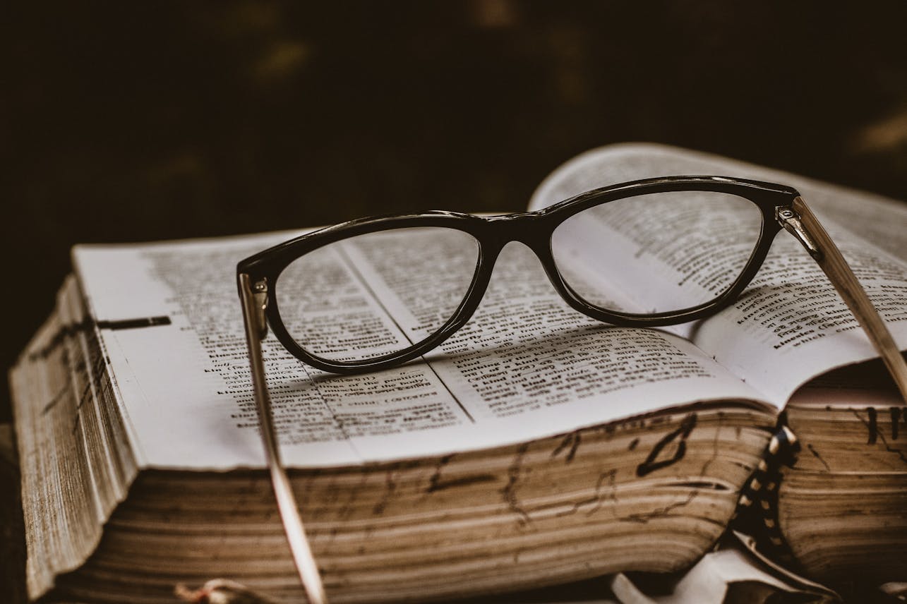 Close-up of eyeglasses on an open book, symbolizing study and knowledge.