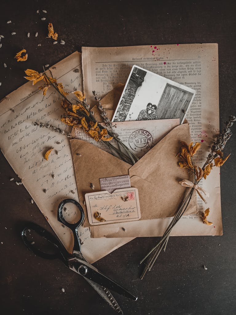 Am Dachboden finden sich oft alte Fotos und Dokumente; Ahnenforschung für Anfänger; Charming vintage arrangement with dry flowers, envelopes, and old photographs in a rustic setting.