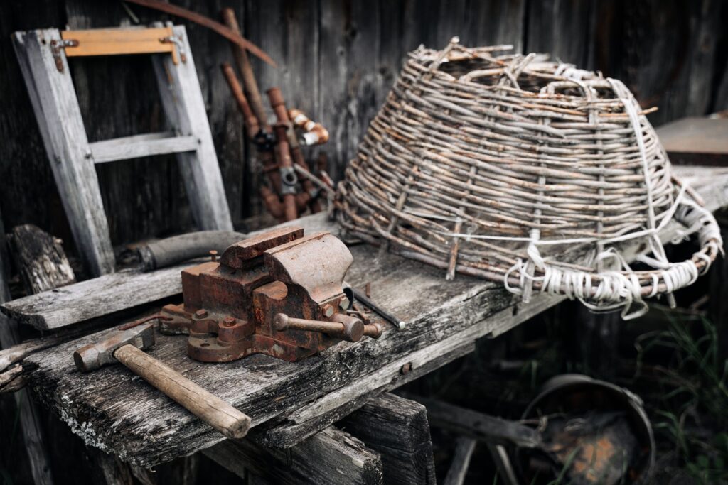 A vintage workbench with old rusty tools and a woven basket, showcasing rustic charm.